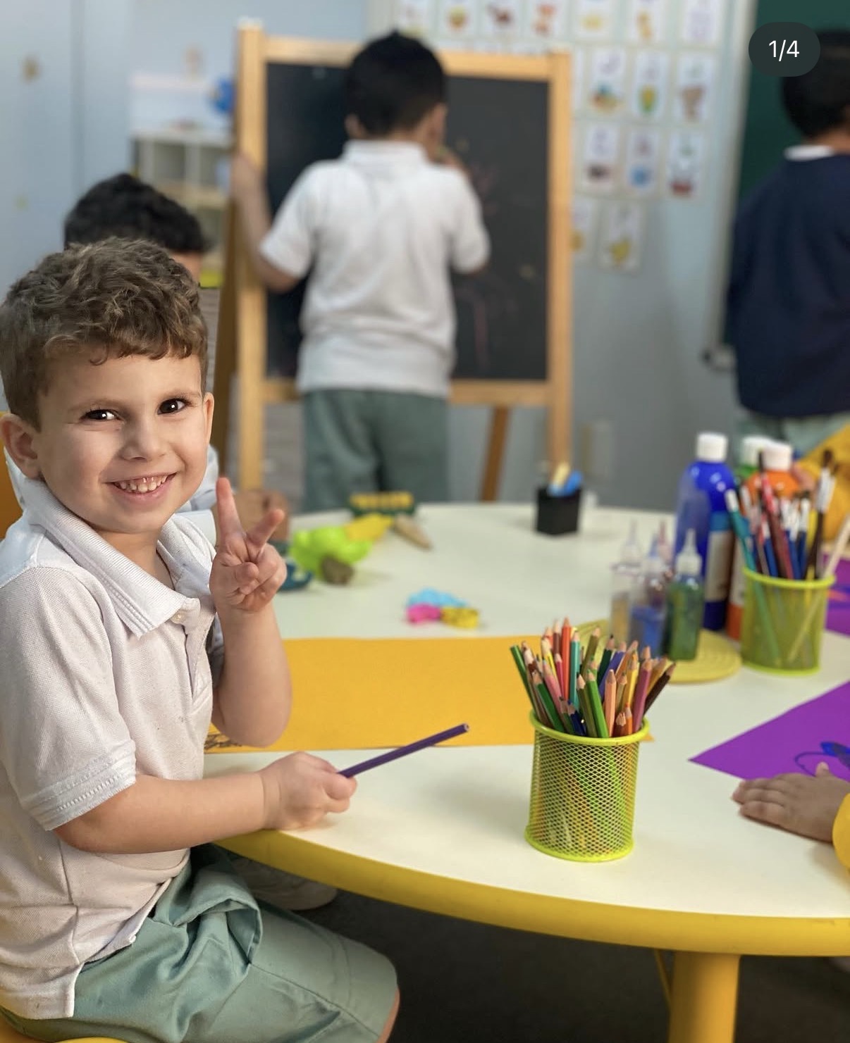 طفل يبتسم أثناء الرسم على طاولة الأنشطة مع أصدقائه